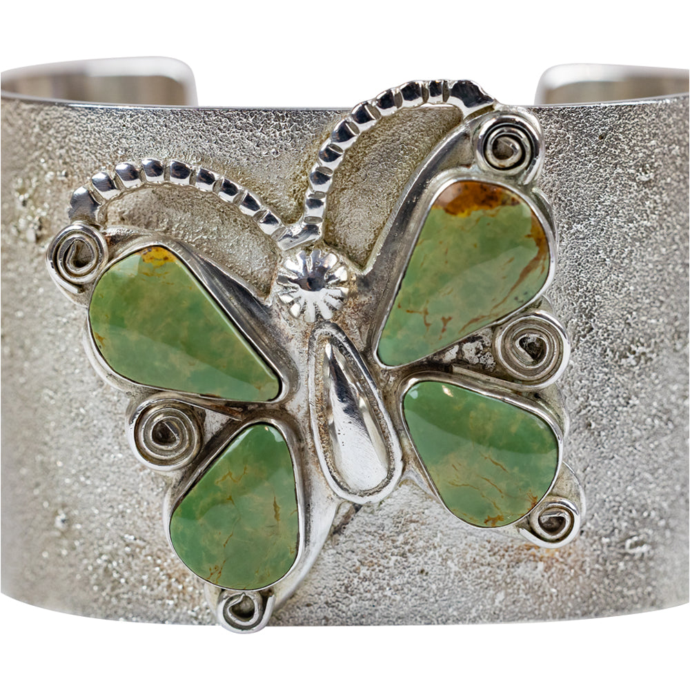 Silver bracelet with green stone accents  in a butterfly shape on a white background
