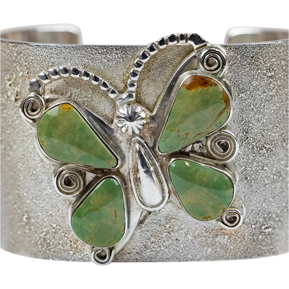 Silver bracelet with green stone accents  in a butterfly shape on a white background
