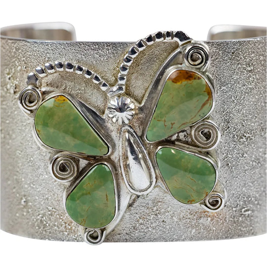Silver bracelet with green stone accents  in a butterfly shape on a white background