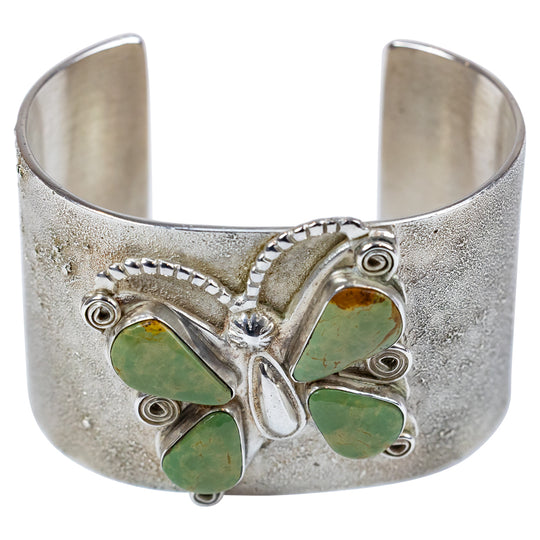 Silver cuff bracelet with green stone butterfly design on a white background