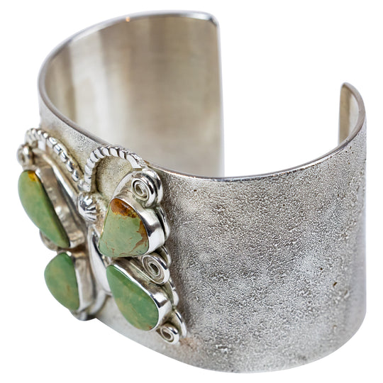 Silver cuff bracelet with green stone butterfly design on a white background