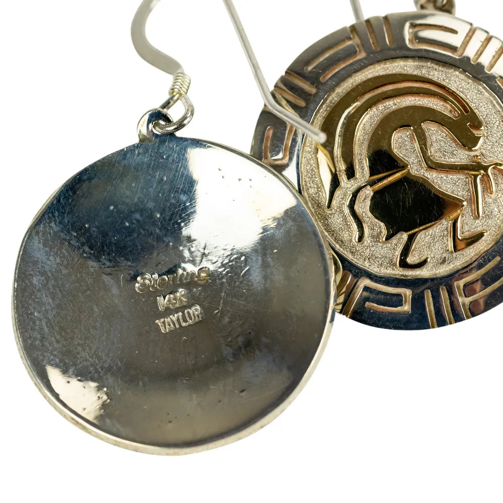 Close-up of two gold and silver earrings on a white background