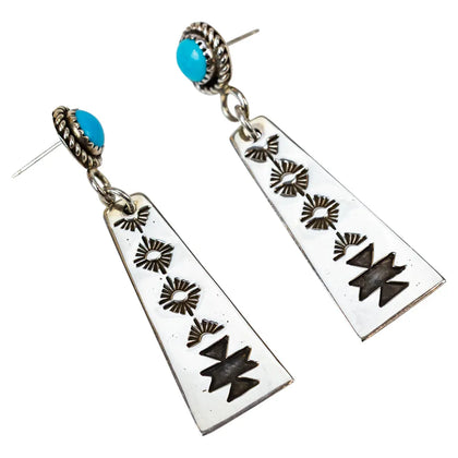Pair of earrings with geometric designs and turquoise stones on a white background