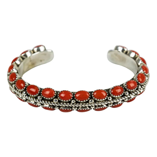 Silver Navajo bracelet with coral stones on a white background