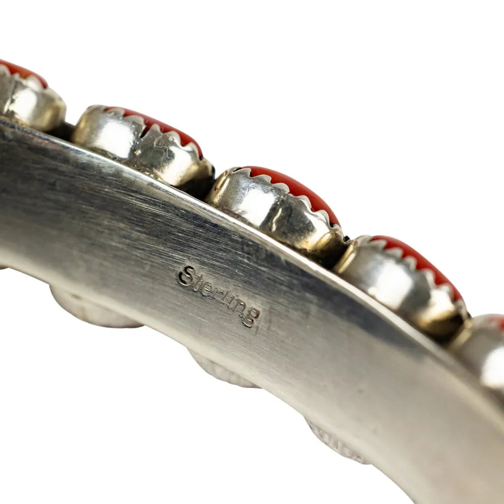 Close-up of a silver and red jewelry piece with 'Sterling' engraving on a white background