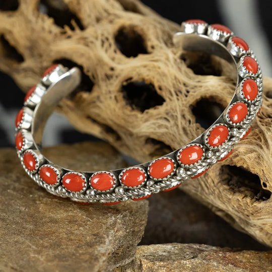 Silver Navajo bracelet with Mediterranean coral stones on a textured stone surface