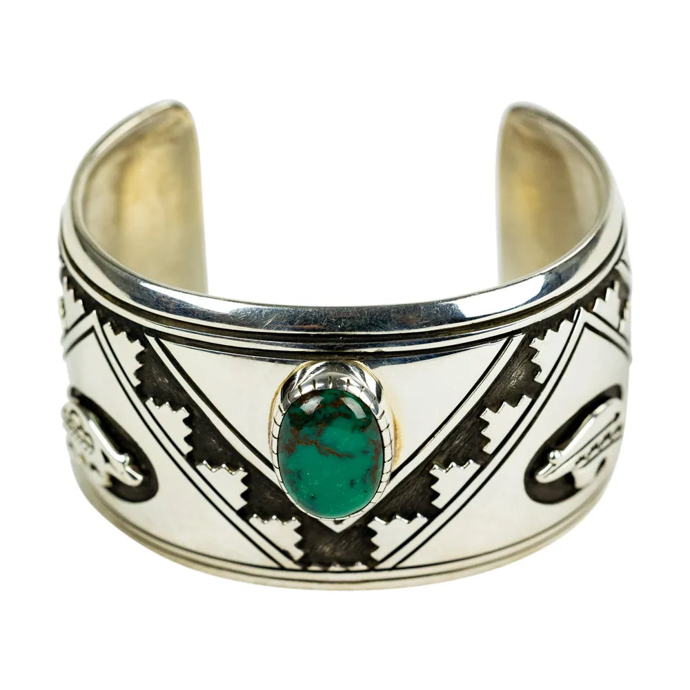 Silver cuff bracelet with a green stone on a white background