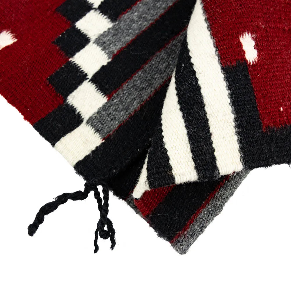 Close-up of a Navajo rug with red, black, and white pattern on a white background
