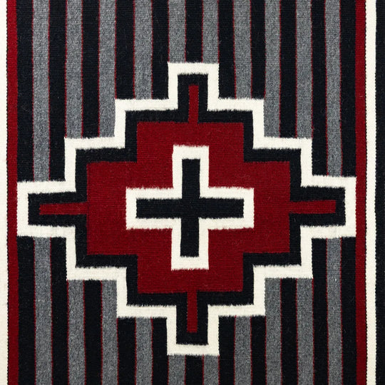 Geometric patterned rug with red, black, and white design on a striped background