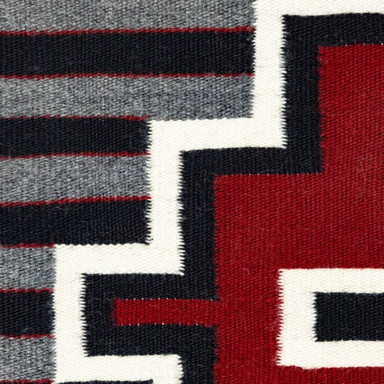 Close-up of a geometric patterned fabric with red, black, and gray colors.