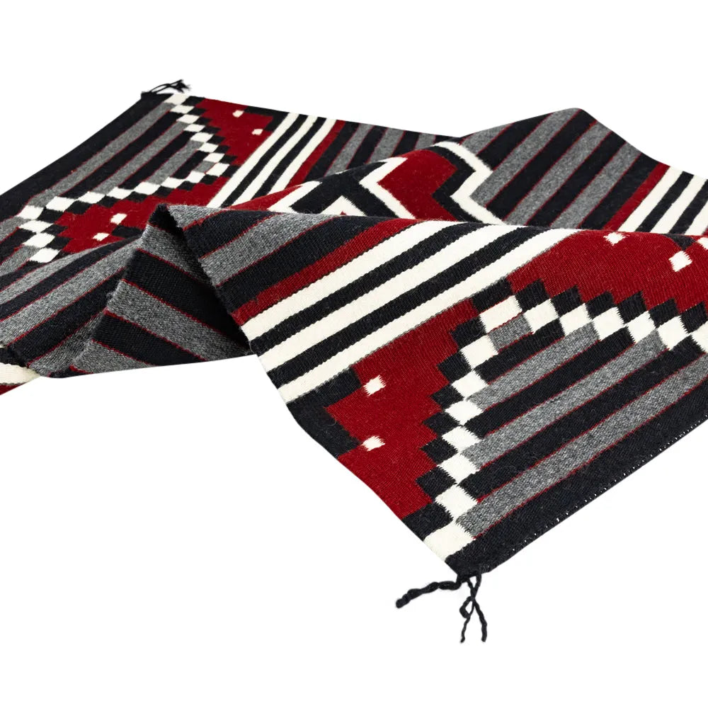 Woven textile with red, black, and white geometric pattern on a white background