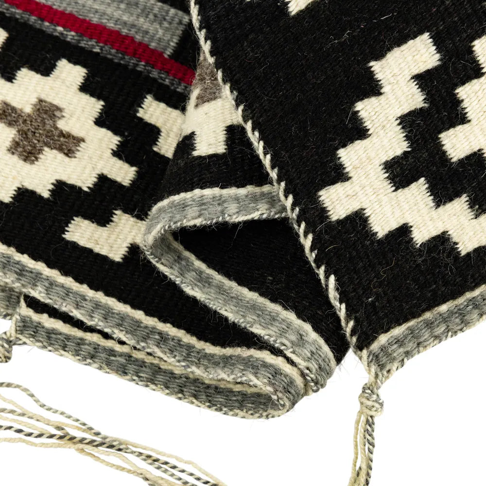 Close-up of a woven Navajo rug with geometric patterns on a white background