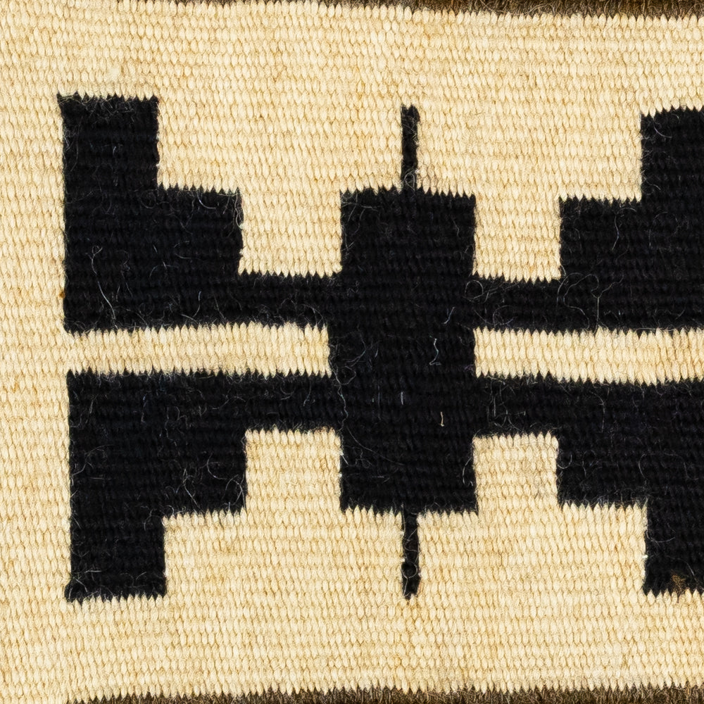 Close-up of a woven textile with black geometric patterns on a beige background