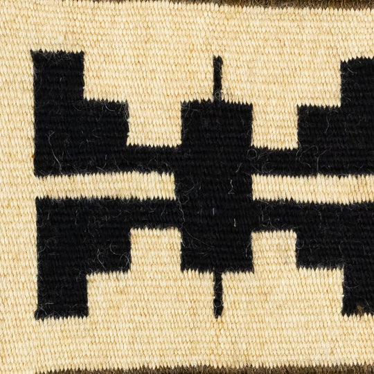 Close-up of a woven textile with black geometric patterns on a beige background