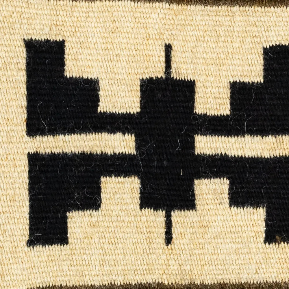 Close-up of a woven textile with black geometric patterns on a beige background
