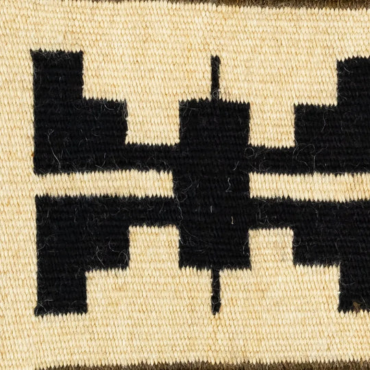 Close-up of a woven textile with black geometric patterns on a beige background