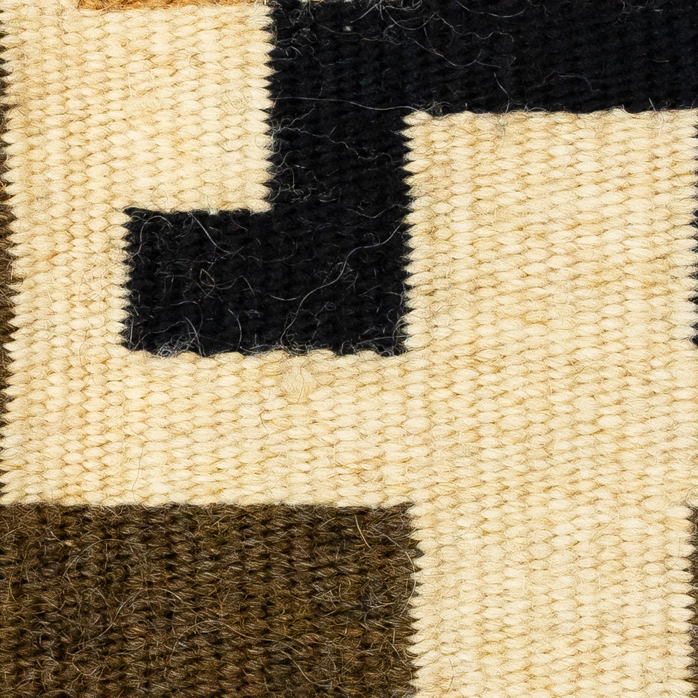 Close-up of a woven rug with black, brown, and beige squares.