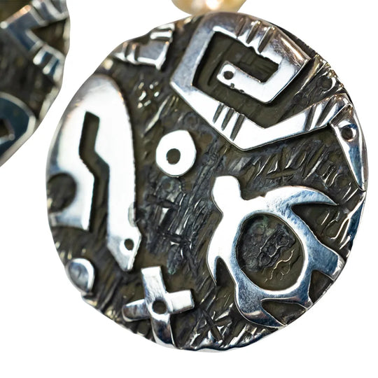 Pair of silver and black patterned earrings on a white background