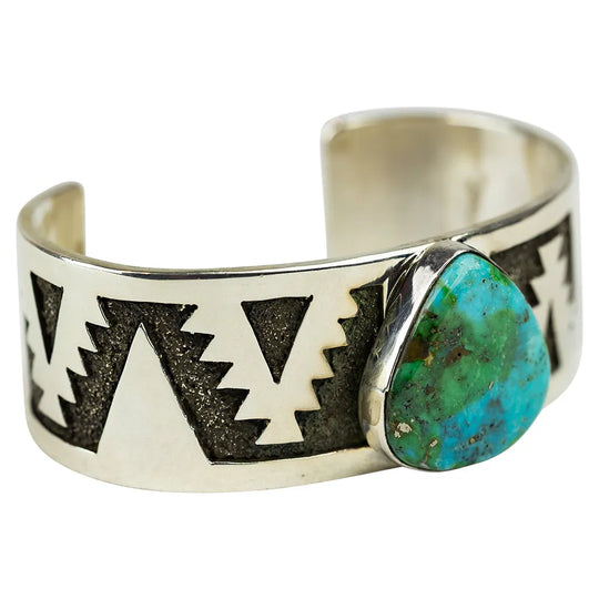 Silver cuff bracelet with design and turquoise stone on a white background