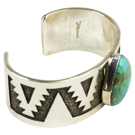 Silver cuff bracelet with geometric design and turquoise stone inside view with hallmark on a white background