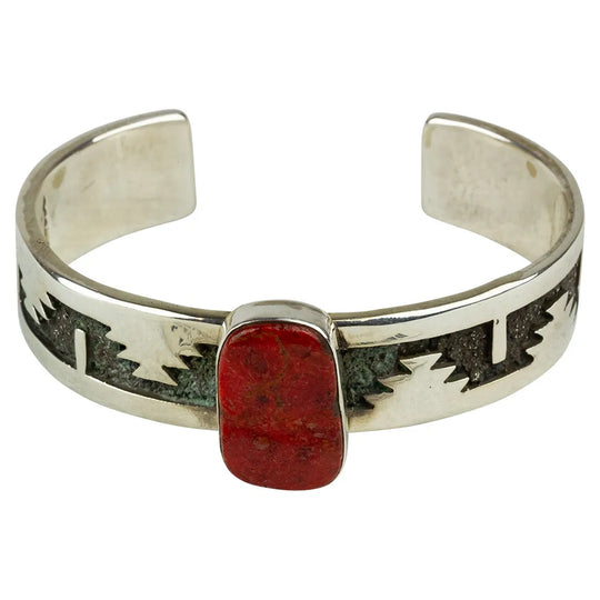 Silver bracelet with red stone and geometric patterns on a white background