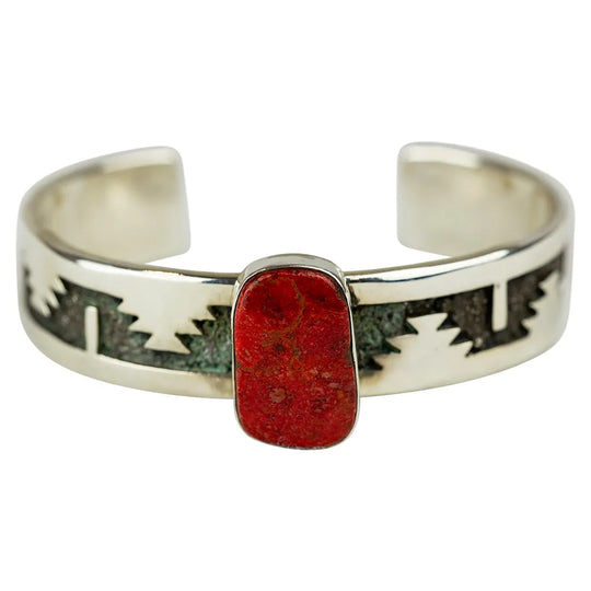 Detail of red coral stone on silver cuff bracelet on white background