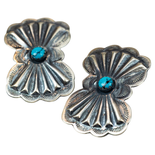 Pair of silver concho-style earrings with turquoise stones on a white background
