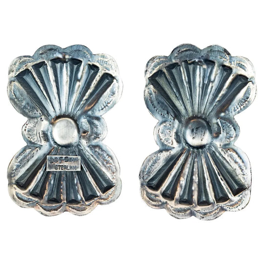 Pair of silver concho-style earrings with turquoise stones on a white background