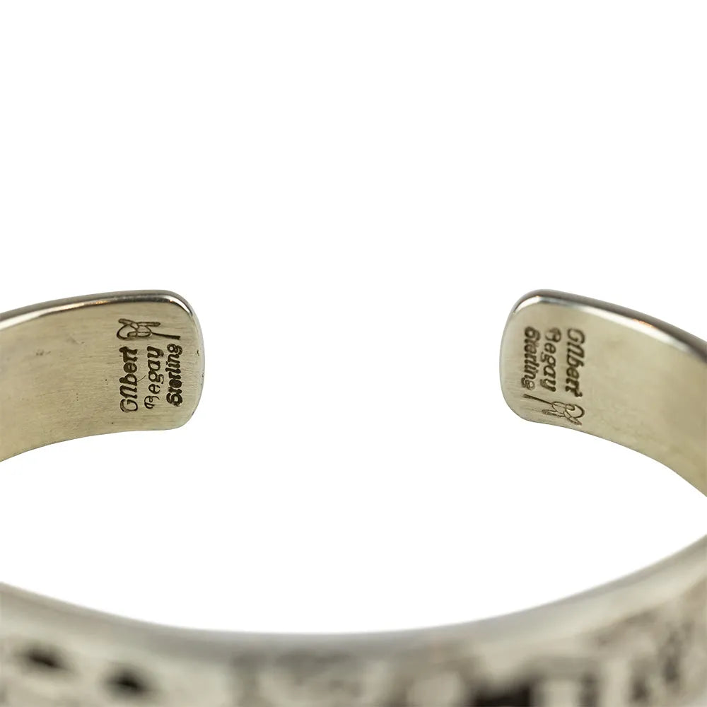 Close-up of a silver bracelet with engraved hallmark on a white background