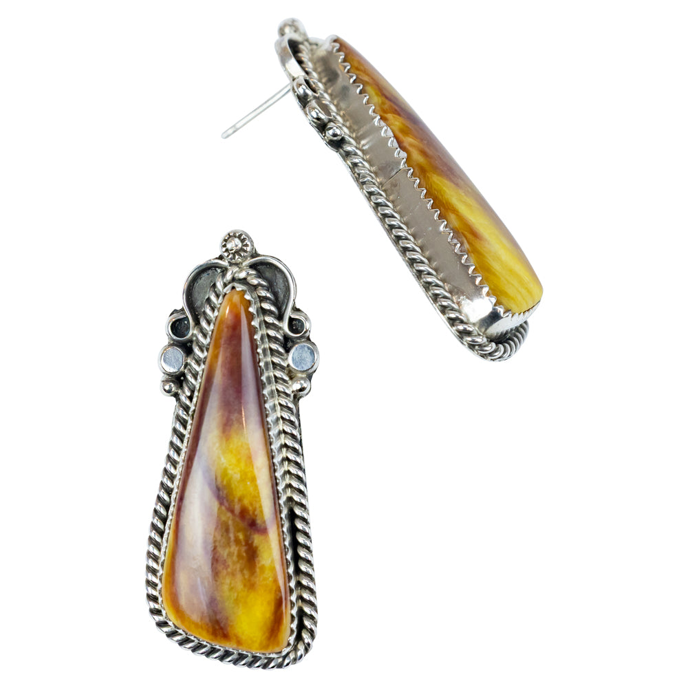 Pair of earrings with teardrop-shaped amber stones and silver frames on a white background