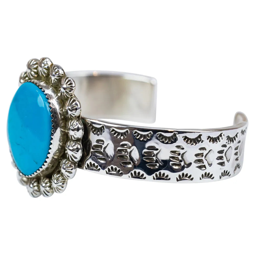 Silver cuff bracelet with blue stone on a white background