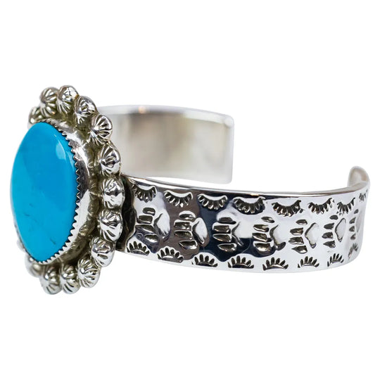 Silver cuff bracelet with blue stone on a white background