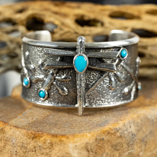 Silver cuff bracelet with turquoise stones on a stone surface