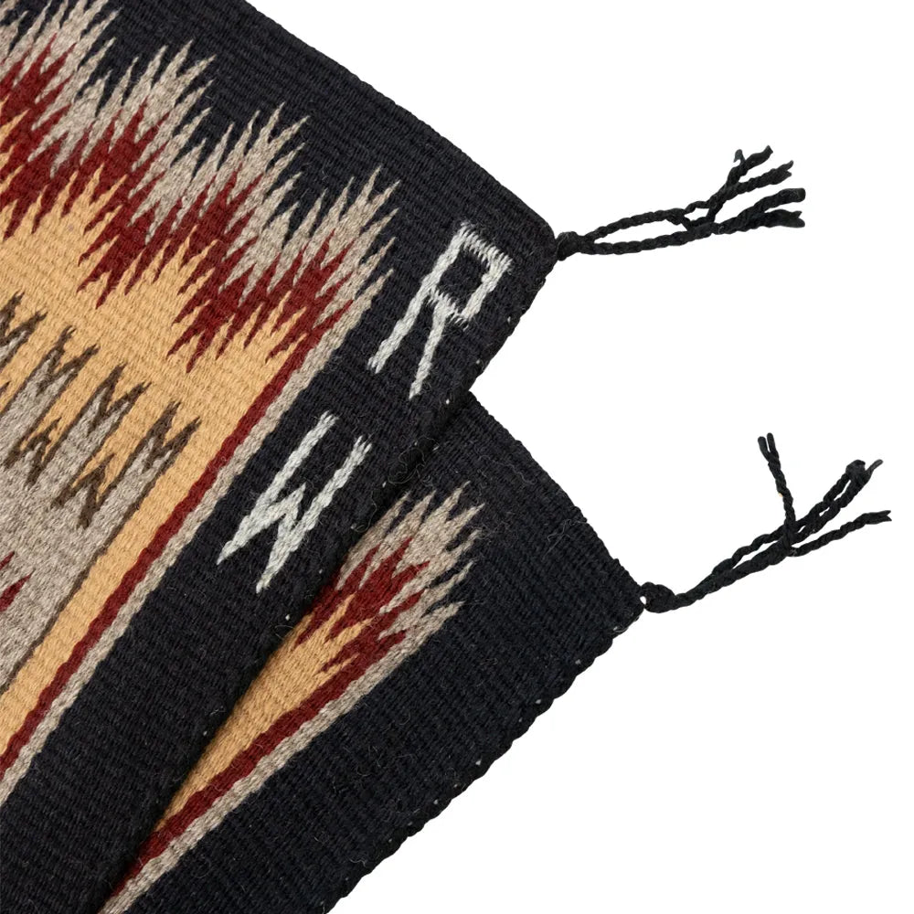 Textile with geometric pattern and tassels on a white background