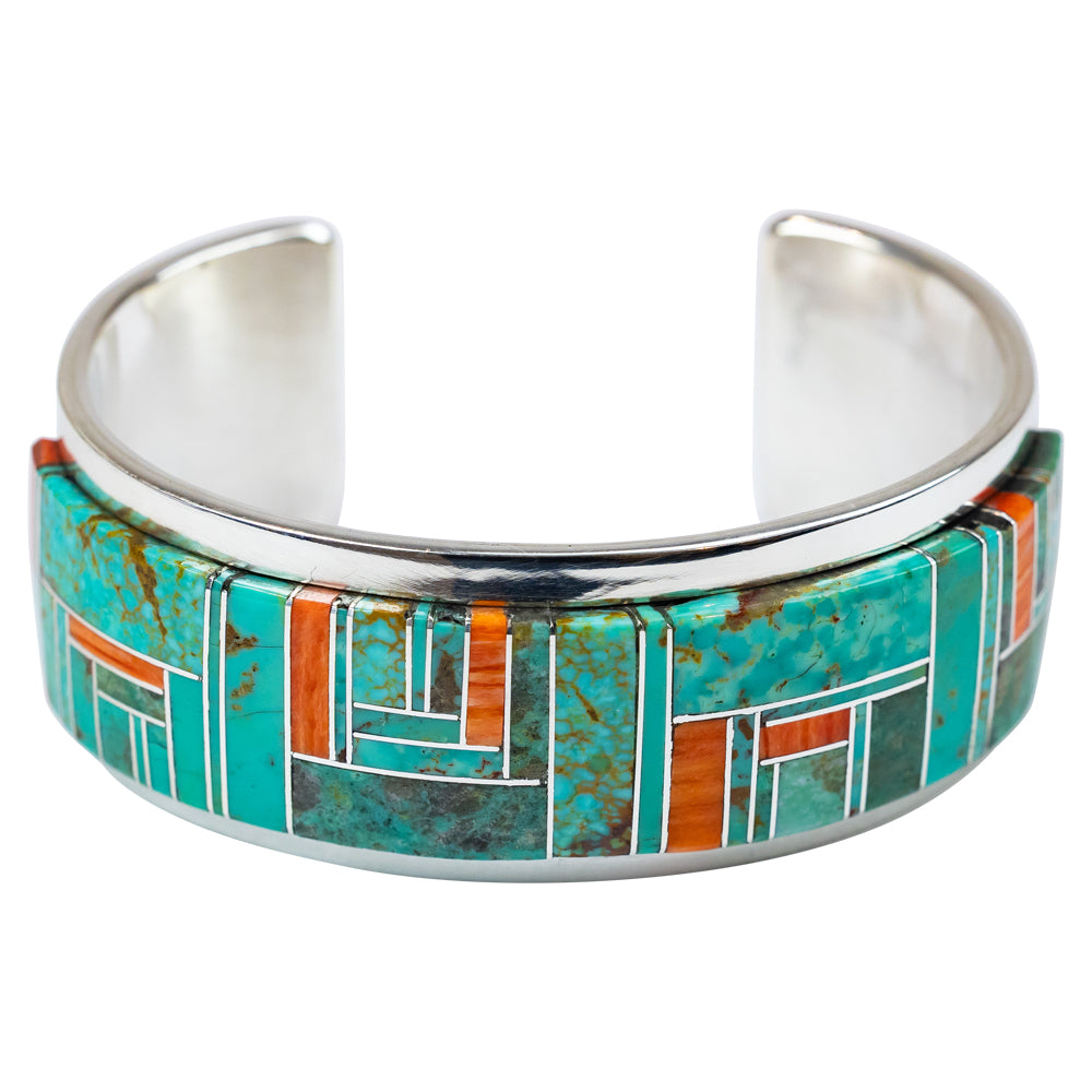 Silver cuff bracelet with turquoise and orange inlay on a white background