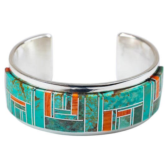 Silver cuff bracelet with turquoise and orange inlay on a white background