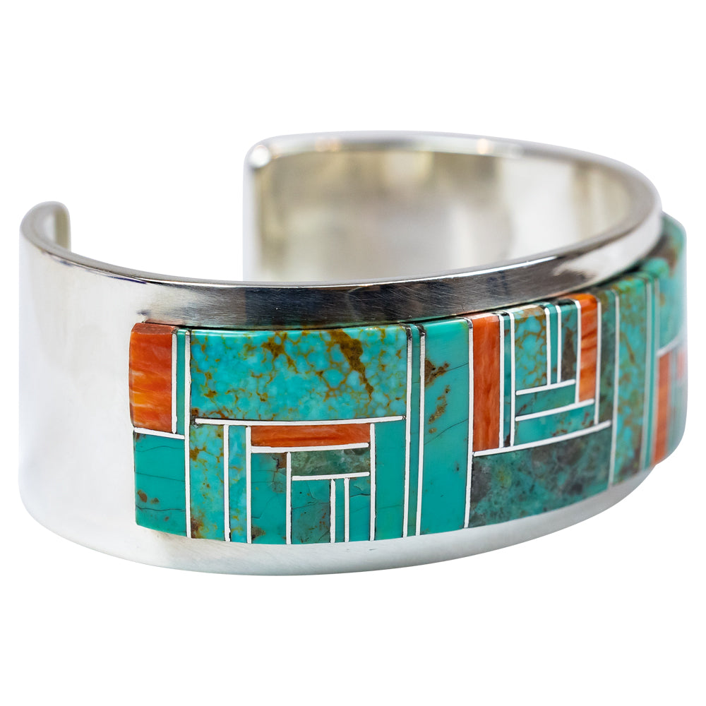 Silver cuff bracelet with turquoise and orange inlay on a white background