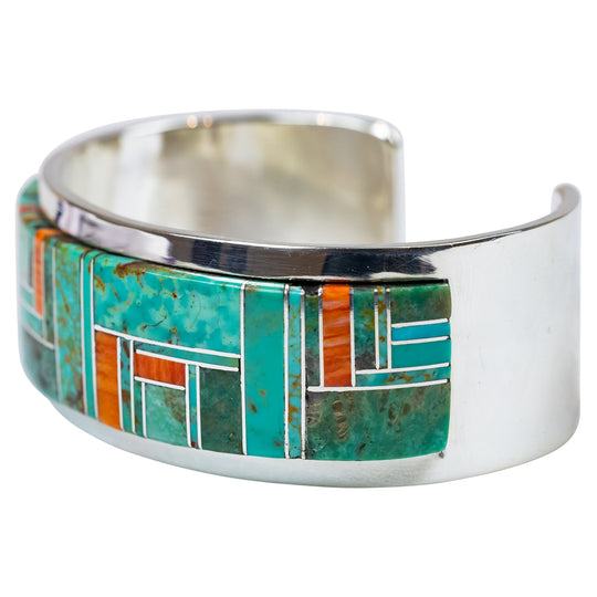 Silver cuff bracelet with turquoise and orange inlay on a white background