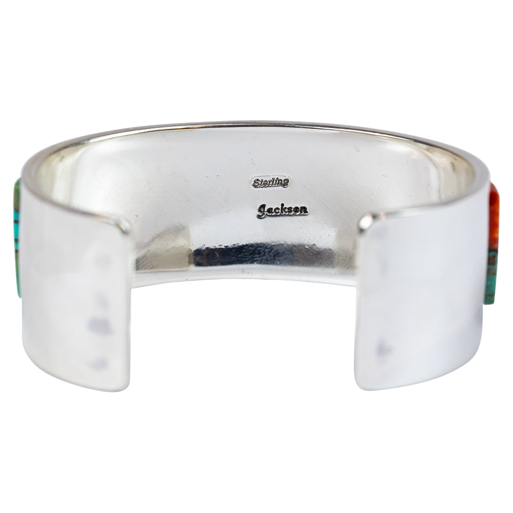 Silver cuff bracelet with turquoise and orange inlay on a white background