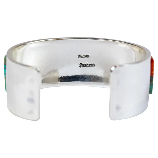 Silver cuff bracelet with turquoise and orange inlay on a white background