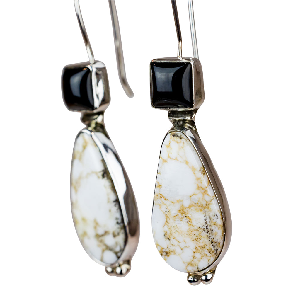 Pair of earrings with teardrop-shaped white stones and black square stones on a white background