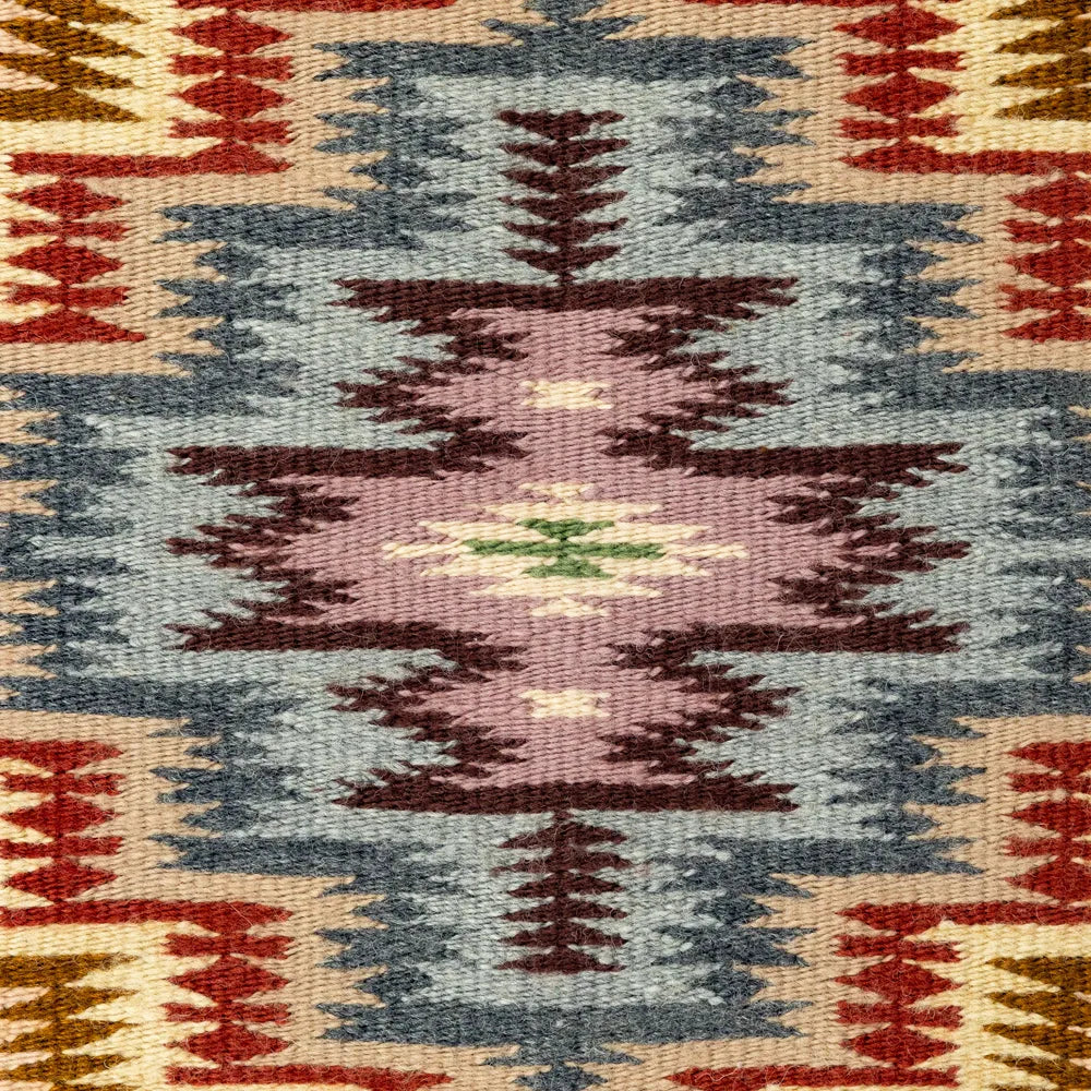 Close-up of a patterned fabric with geometric designs in red, blue, and brown.