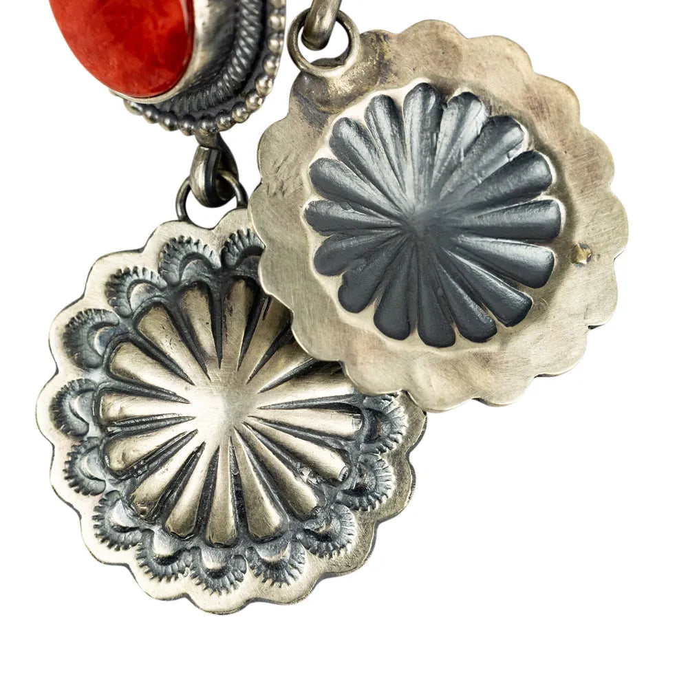 Silver concho-style pendants with a coral stone on a white background