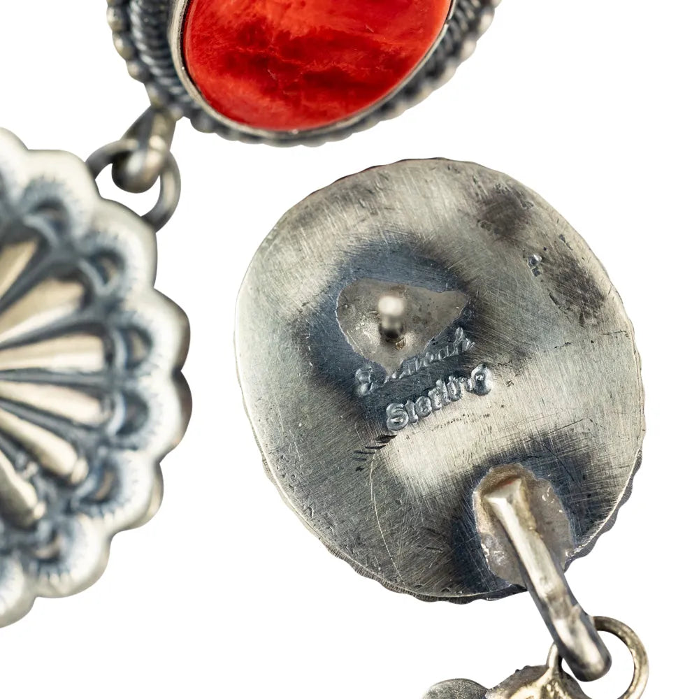 Close-up of a silver earring with a red gemstone on a white background