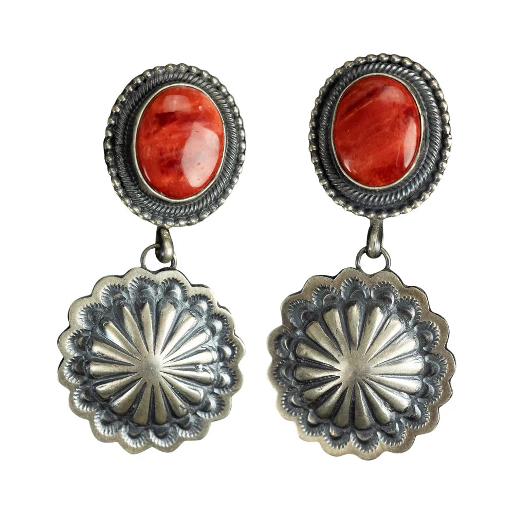 Pair of earrings with red stones and silver concho-style drops on a white background