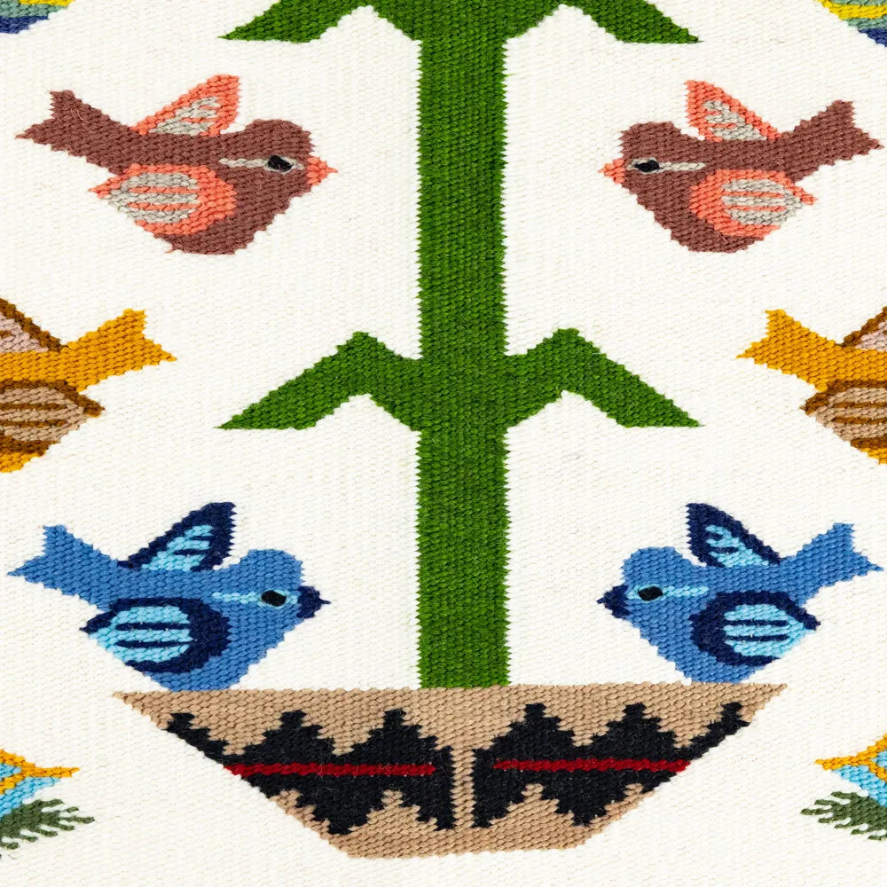 Woven Navajo rug detail with birds and a tree on a white background