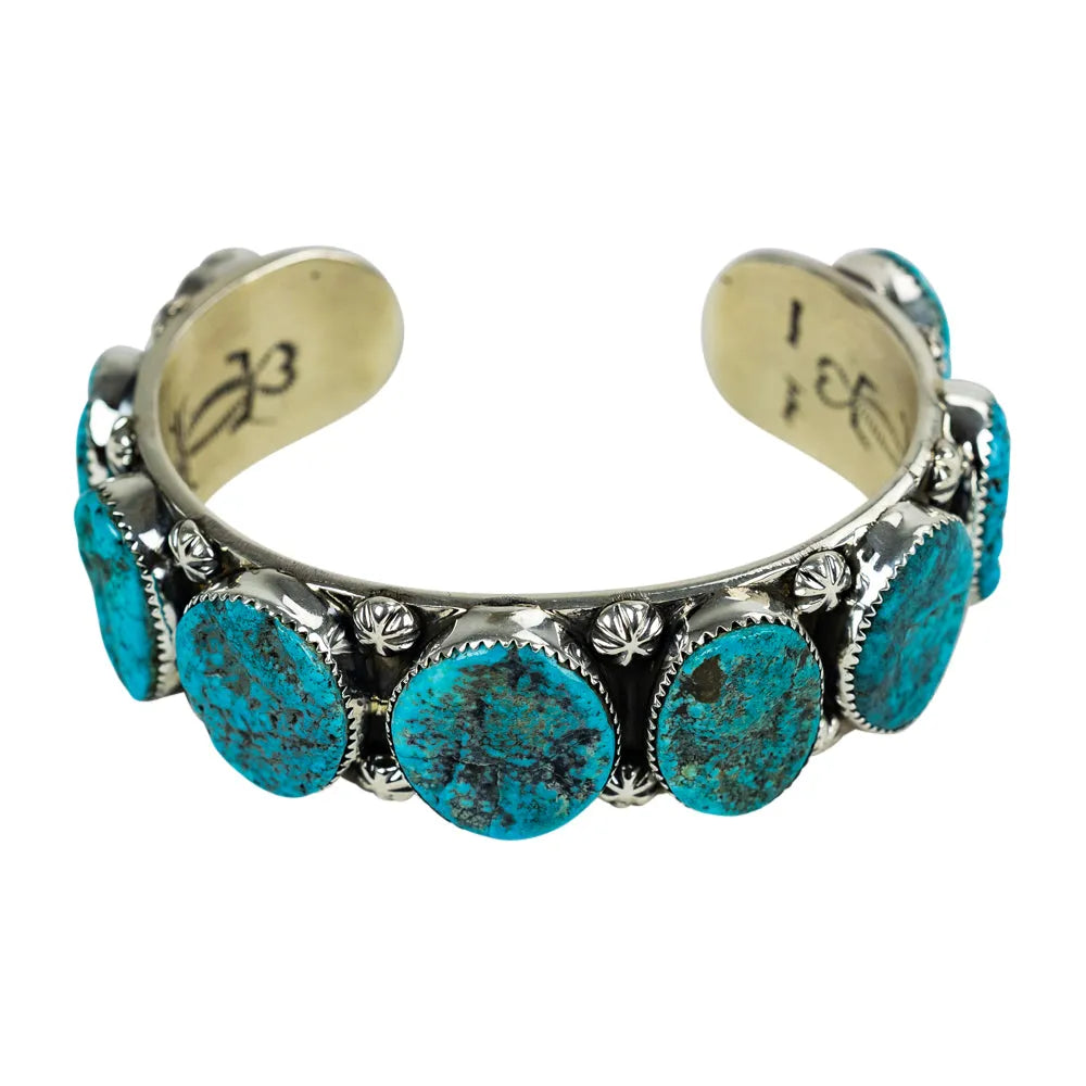 Turquoise stone and sterling silver bracelet with silver accents on a white background