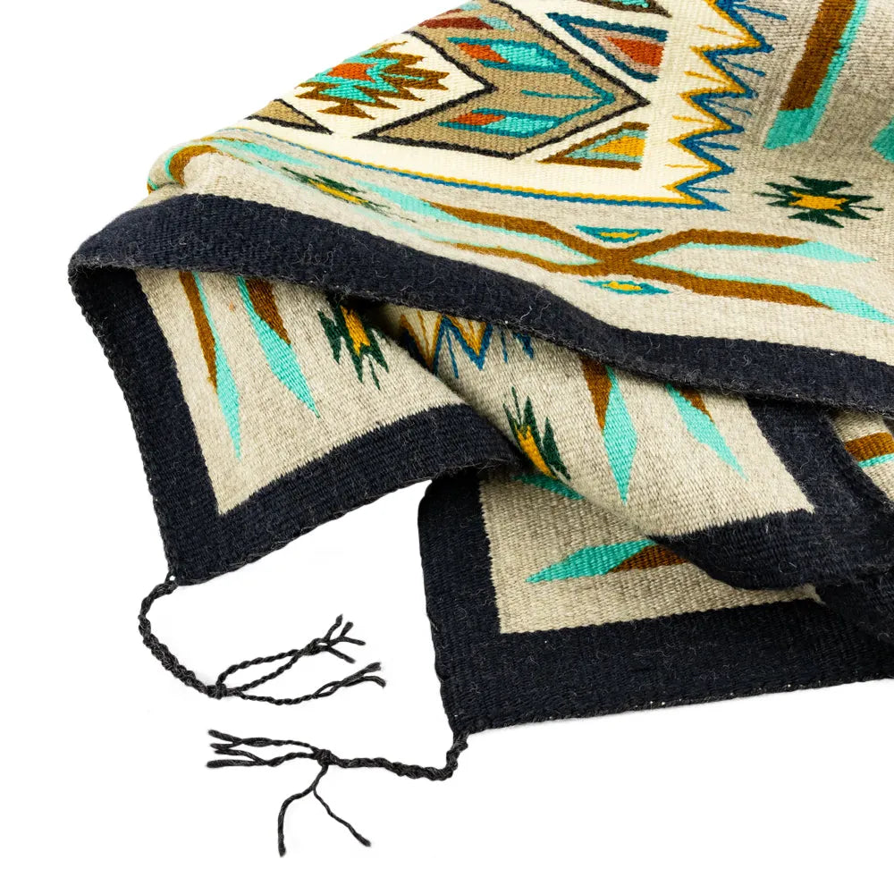 Colorful patterned Navajo rug with tassels on a white background