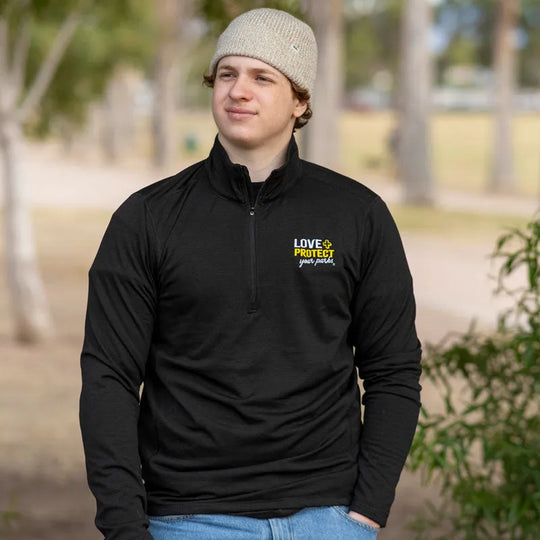 Young man wearing Love + Protect Your Parks® 1/4 Zip Men's Performance Fleece in a park like area.