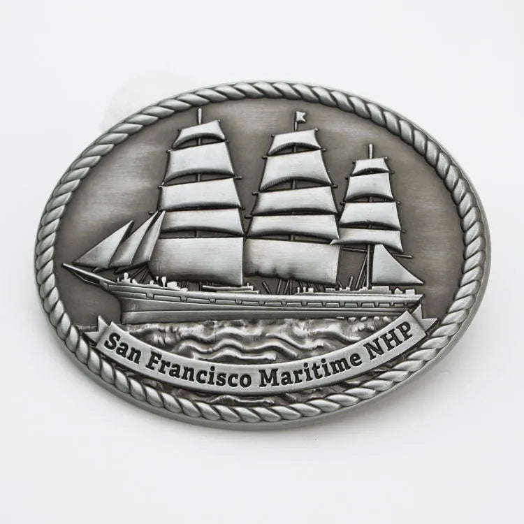 A pewter colored belt buckle featuring an embossed image of a historic ship with the text 'San Francisco Maritime NHP'.